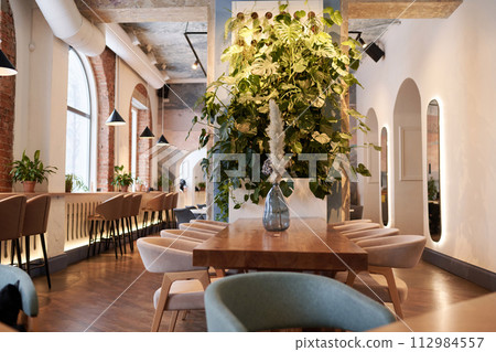 Wide shot of modern fine dining restaurant interior with wooden furniture and green plants, copy space 112984557