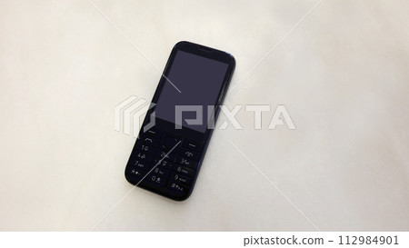 A black obsolete cellphone with blank screen. 112984901