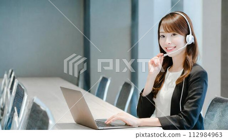 A woman wearing a headset and having a web conference 112984963