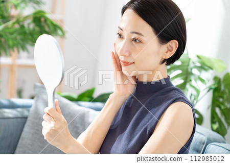 A woman watching a hand mirror A woman watching a hand mirror 112985012