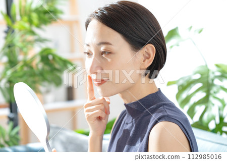 A woman watching a hand mirror 112985016