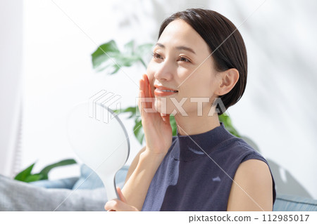 A woman watching a hand mirror A woman watching a hand mirror 112985017