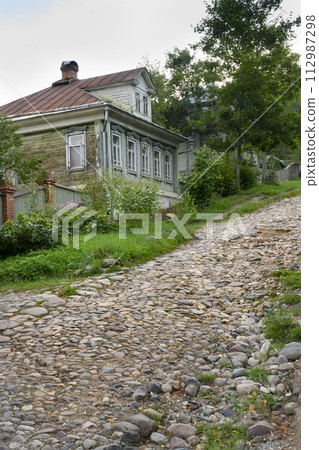A steep stone-paved street with traditional wooden houses in the town of Ples, Russia 112987298
