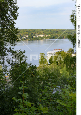 View from the thickets of the forest on the hill to the Volga River with a tourist ship View from the thickets of the forest on the hill to the Volga River with a tourist ship 112987319