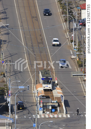 [Vertical composition/person number logo retouched] Hakodate City Tram entering Yachigashira stop and departing 112987785