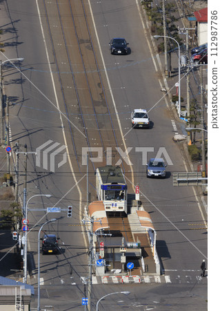 [Vertical composition/person number logo retouched] Hakodate City Tram entering Yachigashira stop and departing 112987786