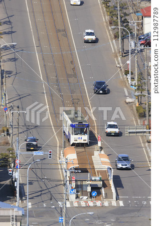[Vertical composition/person number logo retouched] Hakodate City Tram entering Yachigashira stop and departing 112987789