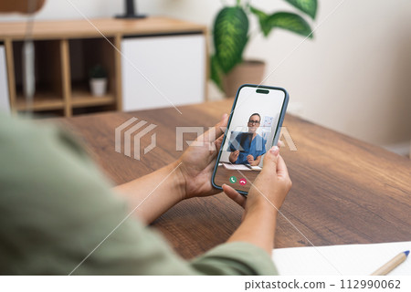 Close-up of a telehealth appointment with a medical professional on a smartphone. Close-up of a telehealth appointment with a medical professional on a smartphone. 112990062
