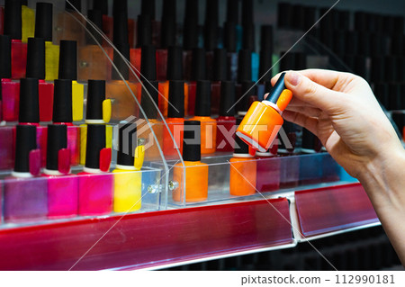 Woman chooses nail polish in a cosmetics store 112990181