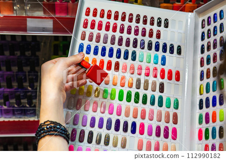 Woman chooses nail polish in a cosmetics store 112990182