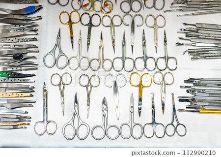 Set of many different scissors for manicure. Metal scissors on a white background. Close-up Set of many different scissors for manicure. Metal scissors on a white background. Close-up 112990210