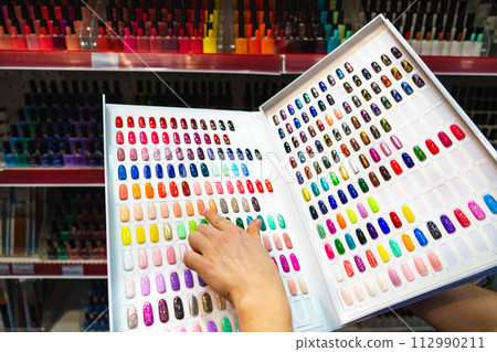 Woman chooses nail polish in a cosmetics store Woman chooses nail polish in a cosmetics store 112990211