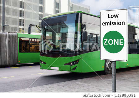 Road sign Low emission ZONE on a background of green electric buses. Road sign Low emission ZONE on a background of green electric buses. 112990381