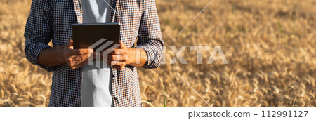 Farmer with digital tablet on an agricultural field. Close up. Smart farming and digital agriculture. 112991127