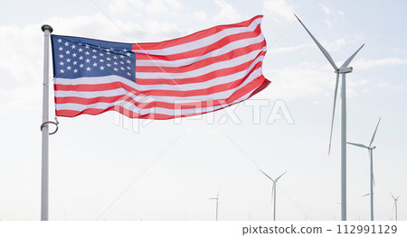 American flag flutters on the backgorund of wind turbines. Symbol of sustainable development United States of America American flag flutters on the backgorund of wind turbines. Symbol of sustainable development United States of America 112991129