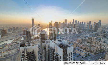 Aerial view of a big modern city with sunset timelapse. Business bay, Dubai, United Arab Emirates. 112991627