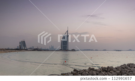 Dubai skyline with Burj Al Arab hotel day to night timelapse. 112991657