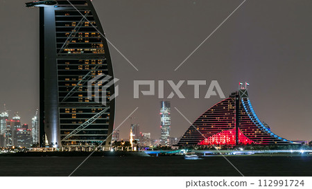 Skyline of Dubai at night timelapse with Burj al Arab in foreground in Dubai, United Arab Emirates 112991724