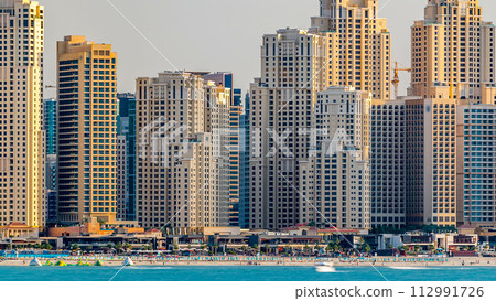 Jumeirah Beach Residence as seen from the palm jumeirah with sea timelapse. Dubai, United Arab Emirates 112991726
