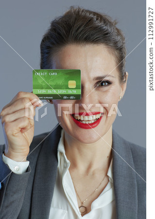 smiling trendy female employee in gray suit isolated on gray 112991727