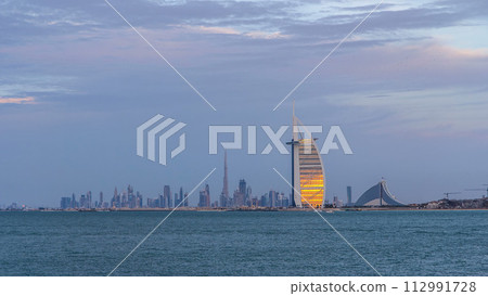 Dubai skyline with Burj Al Arab hotel during sunset and day to night timelapse. Dubai skyline with Burj Al Arab hotel during sunset and day to night timelapse. 112991728
