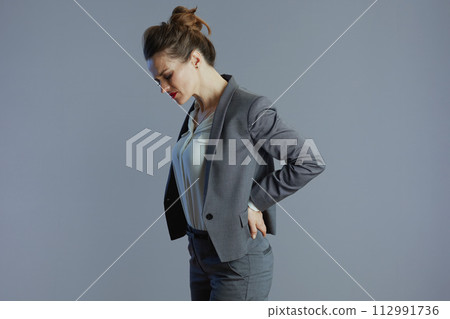 tired elegant woman employee having back pain isolated on grey tired elegant woman employee having back pain isolated on grey 112991736
