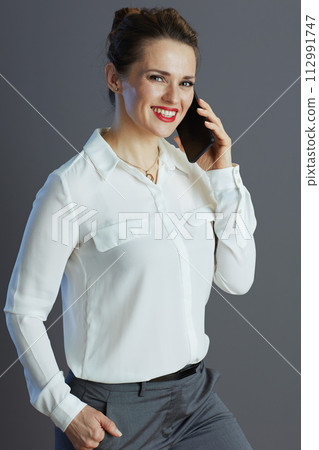happy business owner woman talking on phone against grey happy business owner woman talking on phone against grey 112991747