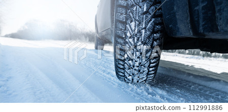 Car is on a snow covered winter road. Close up of winter tire Car is on a snow covered winter road. Close up of winter tire 112991886