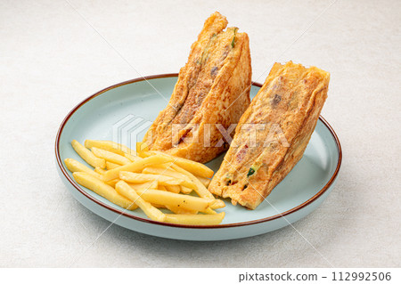 Portion of sandwich fried in egg with french fries Portion of sandwich fried in egg with french fries 112992506