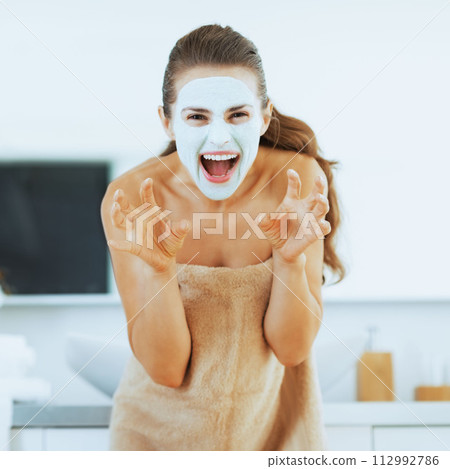 Young woman with cosmetic mask on face scaring 112992786