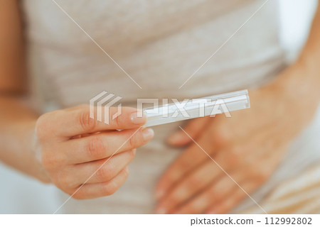 Closeup on young woman holding pregnancy test 112992802