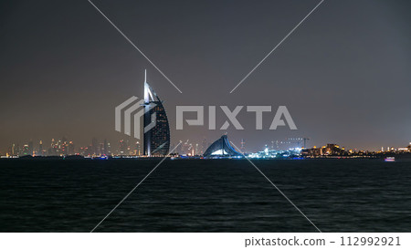 Skyline of Dubai at night timelapse with Burj al Arab in foreground in Dubai, United Arab Emirates 112992921