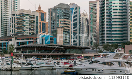 Dubai Marina towers and yachts reflected in water of canal in Dubai day to night timelapse 112993128