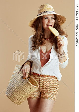 smiling stylish woman in blouse and shorts isolated on beige 112993172