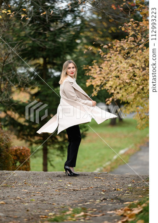 A young girl in an autumn park on a photo shoot, a theme for an autumn calendar. 112993223