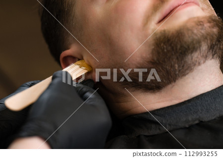 Hair removal procedure in a barbershop. Ear hair wax removal. Hair removal procedure in a barbershop. Ear hair wax removal. 112993255