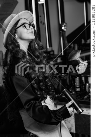 Female portrait of a hairdresser. A young barber girl blows her hair with air from the dryer. Female portrait of a hairdresser. A young barber girl blows her hair with air from the dryer. 112993295