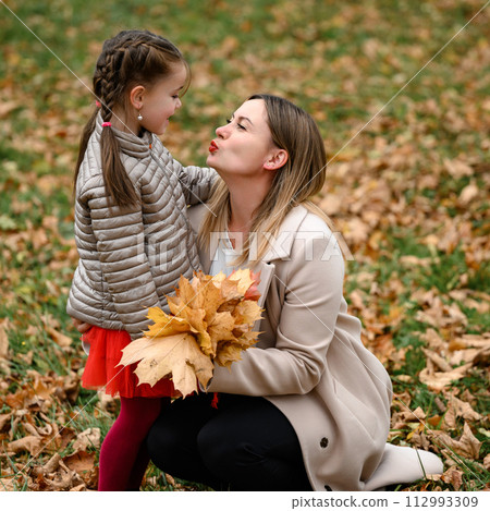 Autumn portrait of a mother with her daughter in the park. Autumn portrait of a mother with her daughter in the park. 112993309