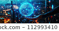 Earth from holographic graphics showing global network connectivity on human hand and blurred city background in the evening in a bird's eye view. 112993410