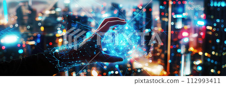 A hand is holding a spherical network graphic, representing future technology where people can control the virtual world through holographic graphics with blur virtual city background. 112993411