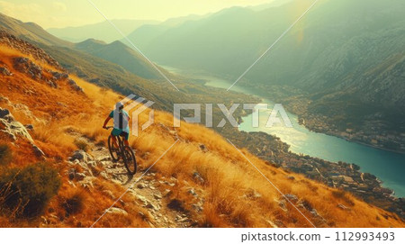 Cyclist Riding the Bike in the Beautiful Mountains Down the Rock on the Sunrise Sky Background. Extreme Sport and Enduro Biking Concept 112993493