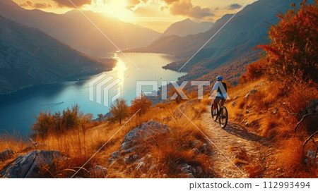 Cyclist Riding the Bike in the Beautiful Mountains Down the Rock on the Sunrise Sky Background. Extreme Sport and Enduro Biking Concept 112993494