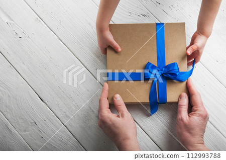 Greeting card Happy Father's Day. Close-up of children's hands giving a gift to their father. Greeting card Happy Father's Day. Close-up of children's hands giving a gift to their father. 112993788