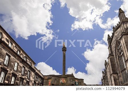 Historic Mercat Cross with golden unicorn stands in Edinburgh Parliament Square against buildings Historic Mercat Cross with golden unicorn stands in Edinburgh Parliament Square against buildings 112994079