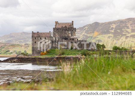 Scottish heritage epitomized by Eilean Donan Castle against backdrop of mountains and loch 112994085