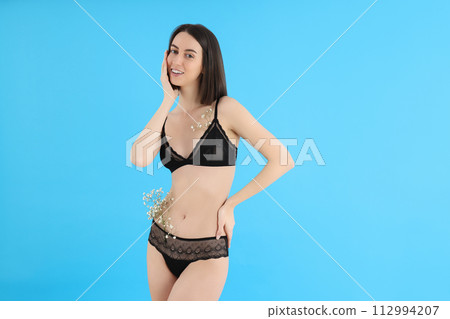 Slim girl in underwear with flowers, on a blue background. Slim girl in underwear with flowers, on a blue background. 112994207