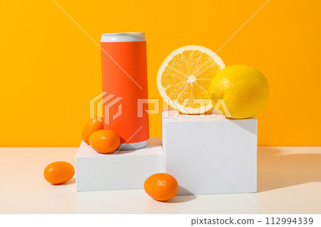 Tin can and citrus fruits on white blocks on orange background 112994339