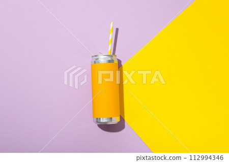 Tin can with straw on yellow and purple background, top view Tin can with straw on yellow and purple background, top view 112994346