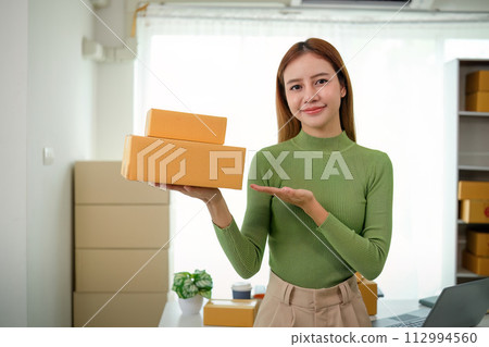 Young business woman asian working online ecommerce shopping at her shop. Young woman sell prepare parcel box of product for deliver to customer. Online selling 112994560