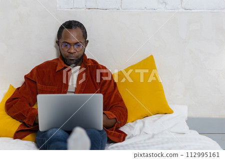 Dark-skinned young man with a laptop working at home 112995161
